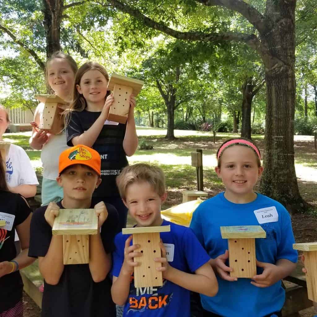 Campers holding bee homes they built at a kids camp
